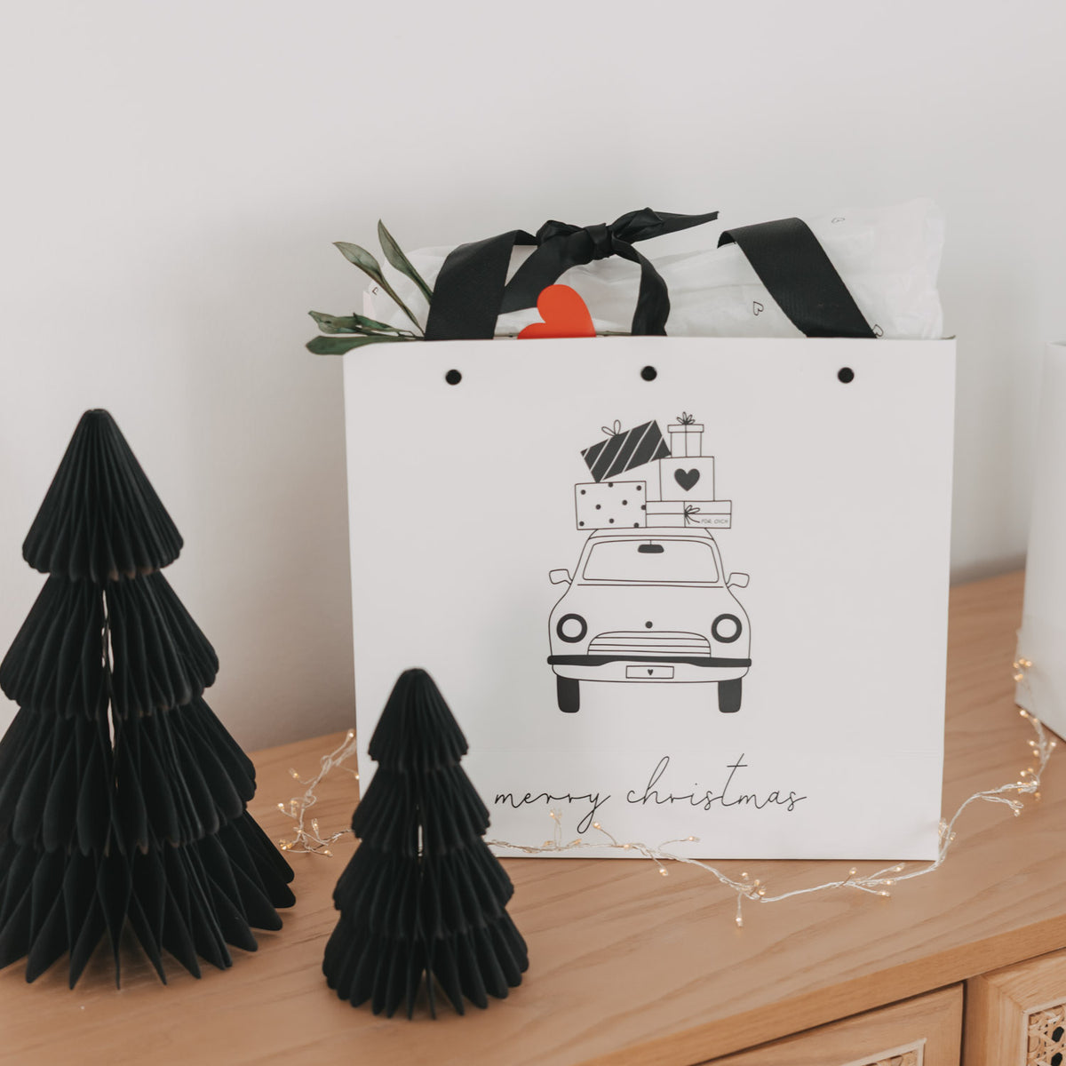 Weiße Geschenktüte mit schwarzem Henkel-Schleifenband, Weihnachtsauto-Print und „merry christmas“