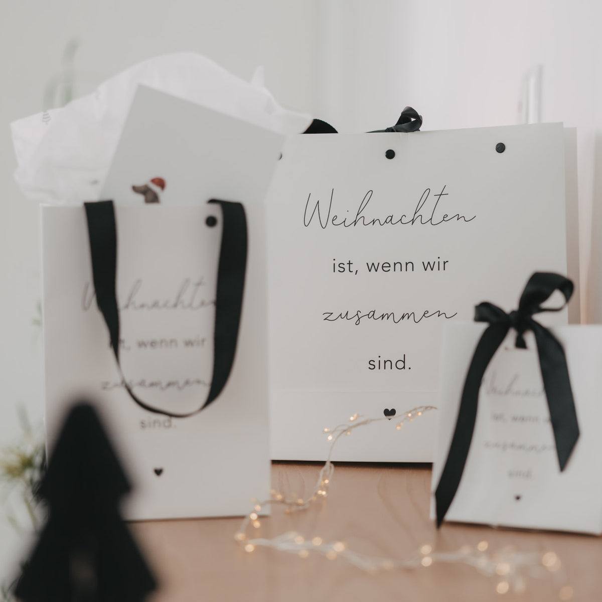 Weiße Mini-Geschenktüten mit schwarzer Schleife und Aufdruck „Weihnachten ist, wenn wir zusammen sind“