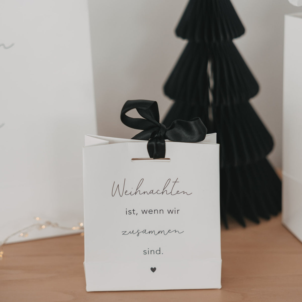 Weiße Mini-Geschenktüte mit schwarzer Schleife, Text „Weihnachten ist, wenn wir zusammen sind.“