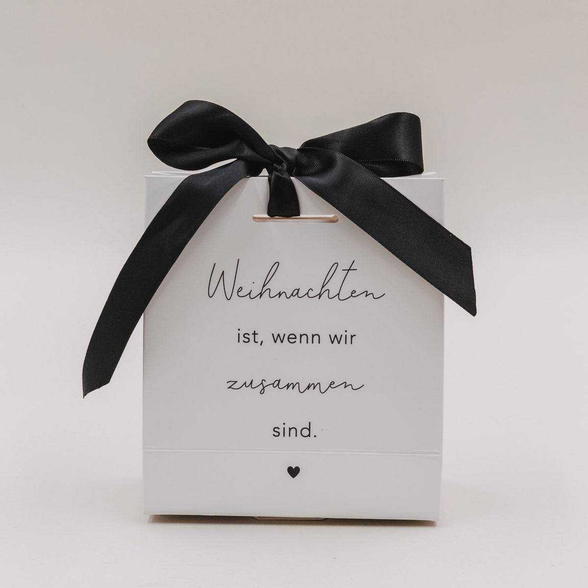 Weiße Mini-Geschenktüte mit schwarzer Schleife, Schriftzug „Weihnachten ist, wenn wir zusammen sind.“