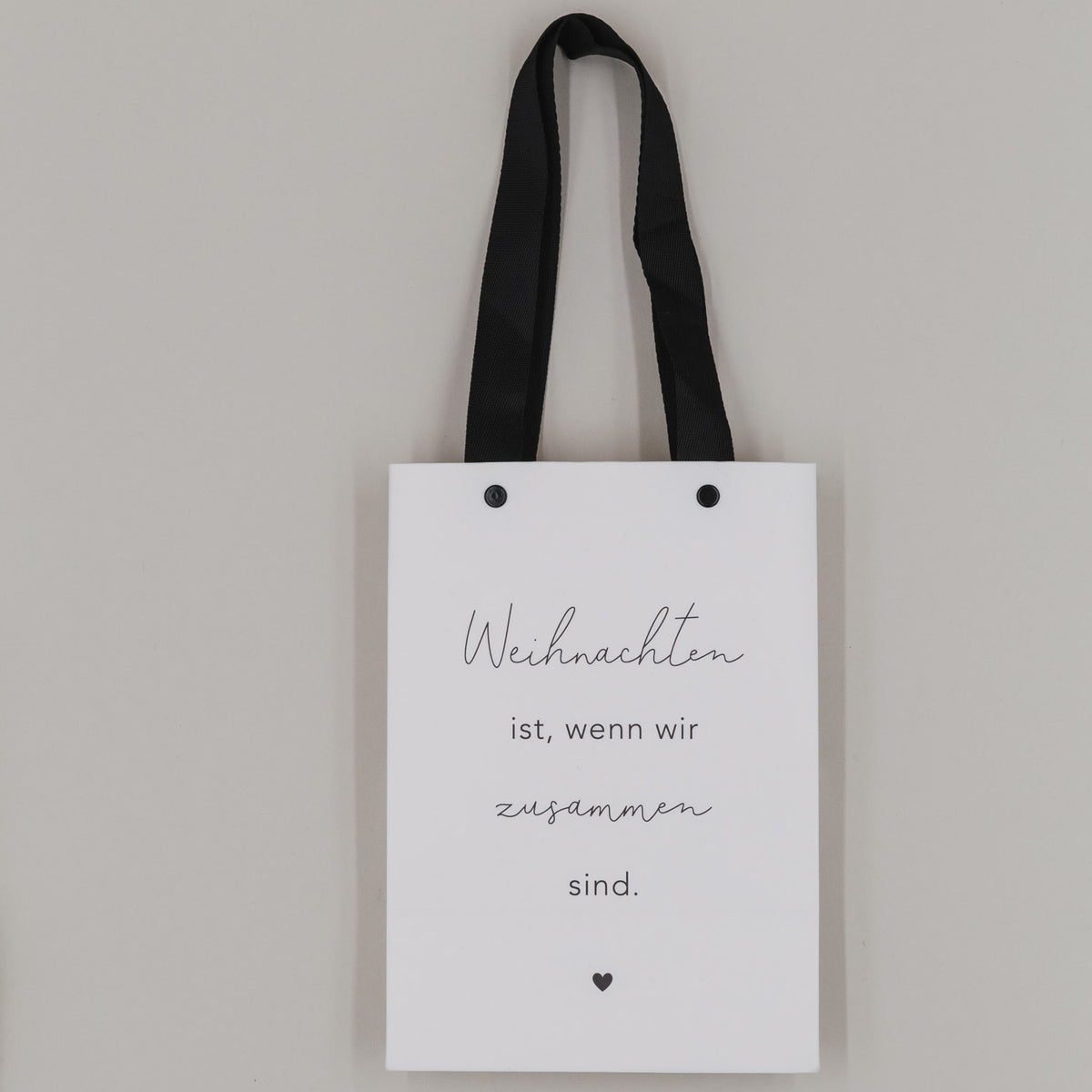 Weiße Geschenktüte mit schwarzen Henkeln und Aufdruck „Weihnachten ist … zusammen sind“