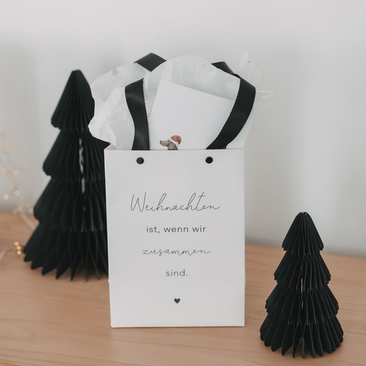 Weiße Geschenktüte im Set mit schwarzen Tragegriffen und Schriftzug „Weihnachten ist“