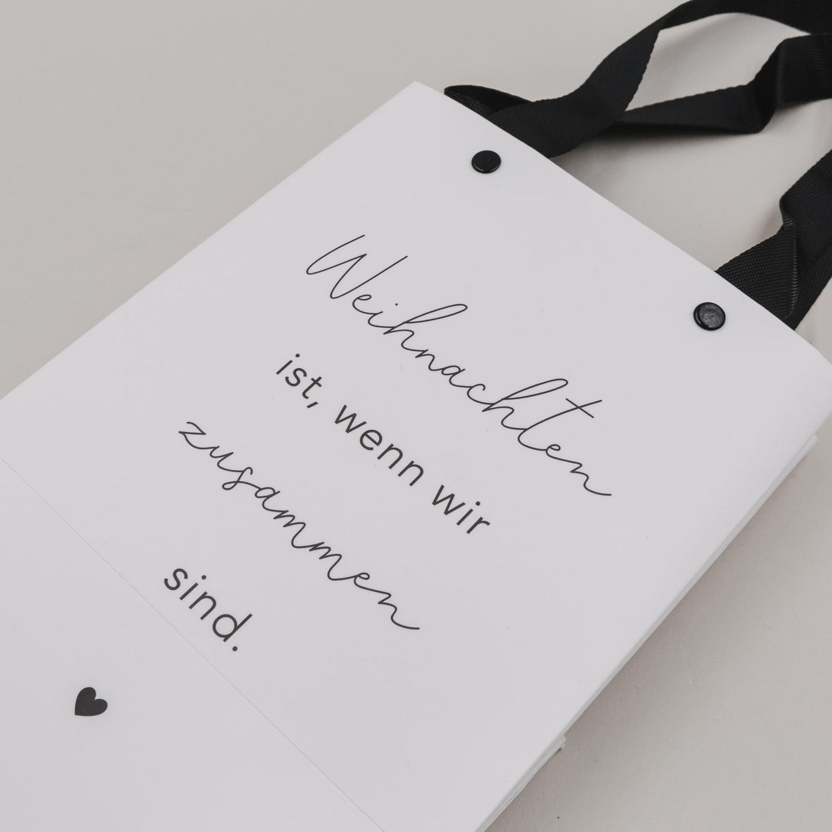 Detailansicht weiße Geschenktüte mit handschriftlichem Text „Weihnachten ist, wenn wir…“