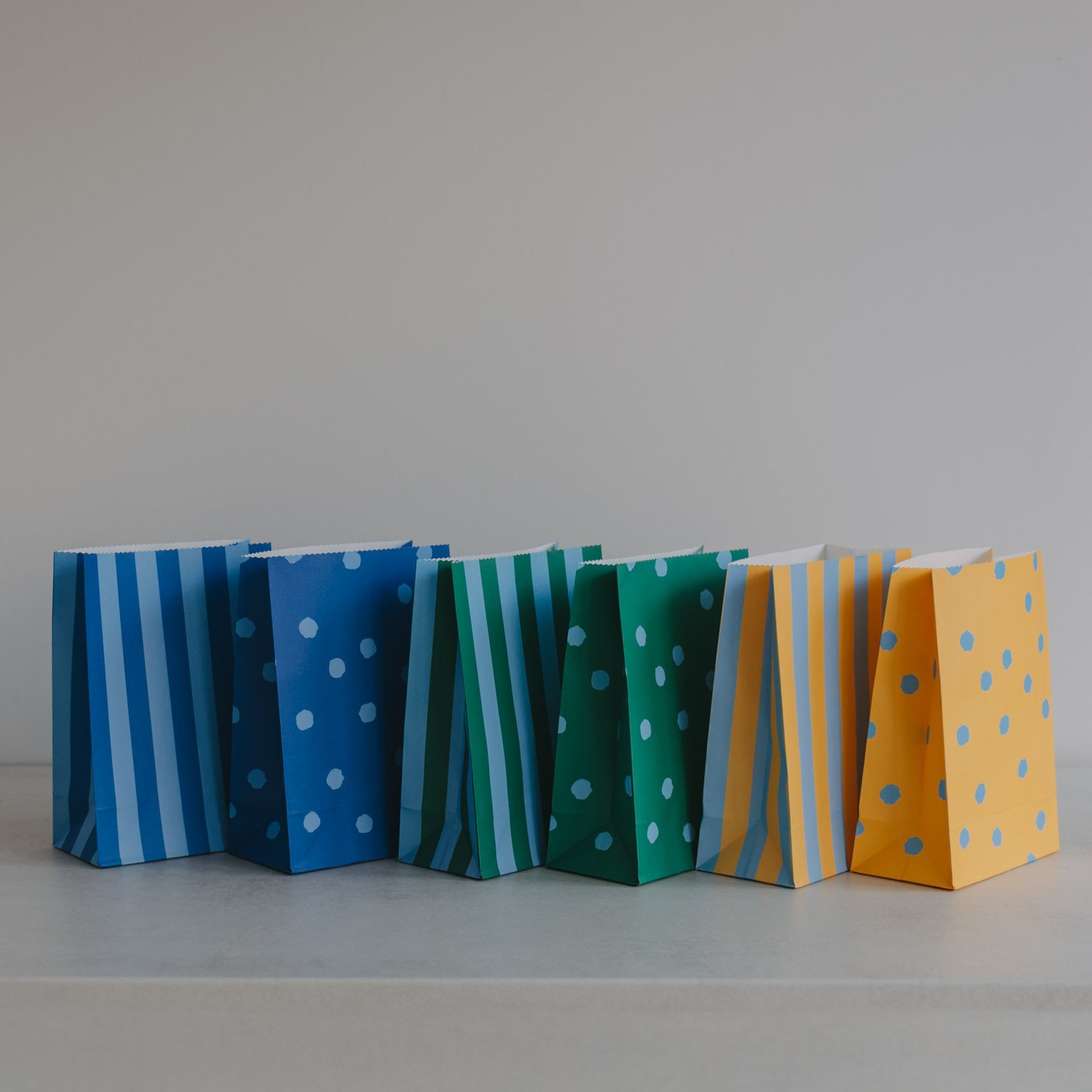 Papiertüten aus Papier: mehrere Tüten mit Streifen und Punkten in Blau, Grün und Gelb