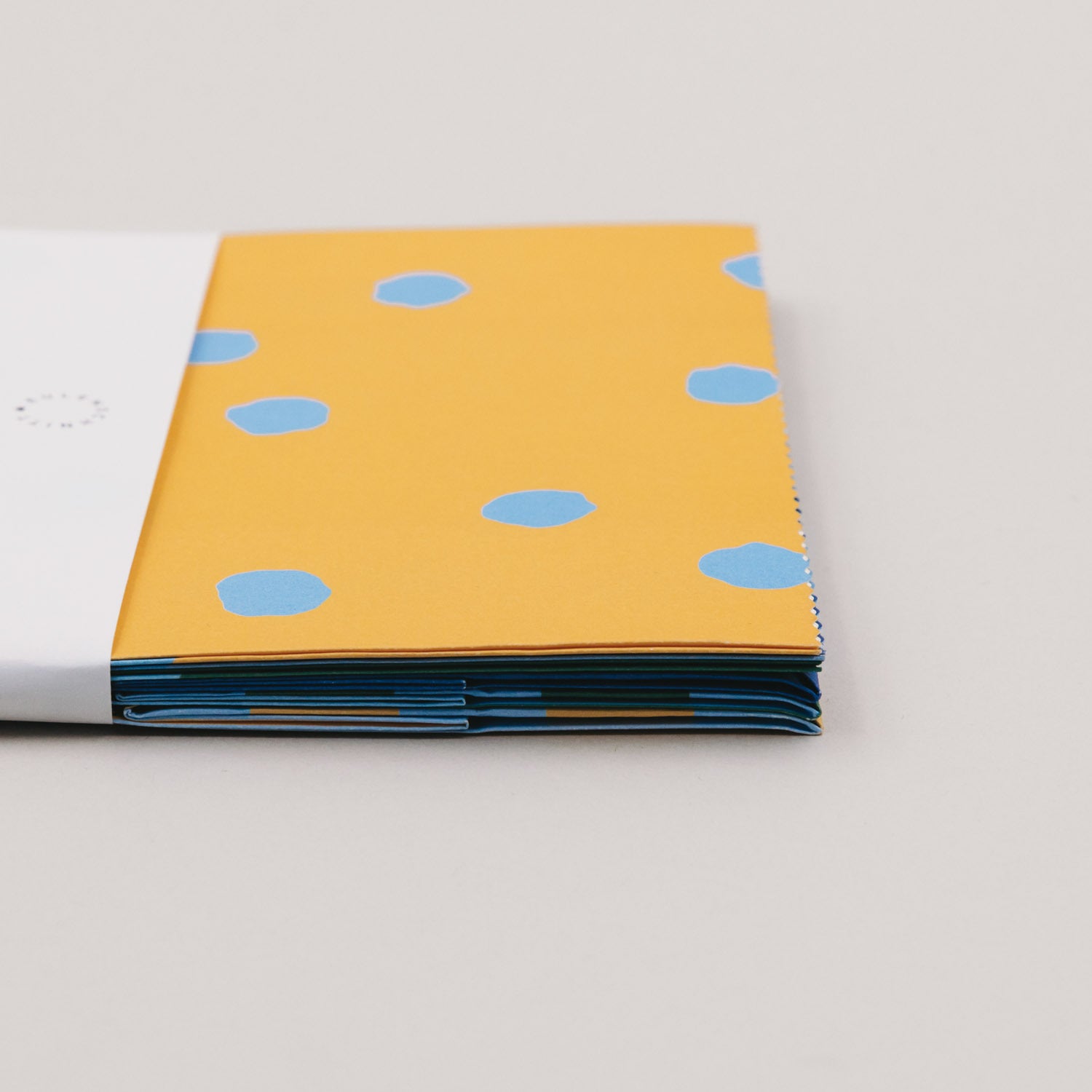 Papiertüten-Stack mit gelber Fläche und blauen Punkten, Kanten mit Streifen