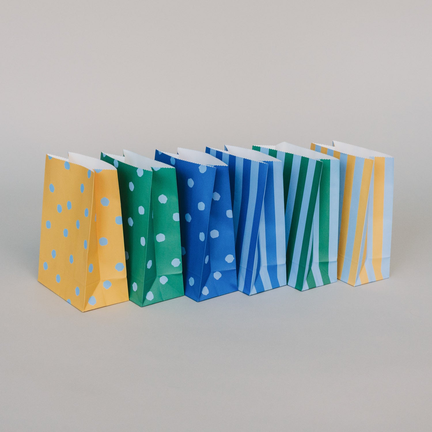 Papiertüten im 6er-Set nebeneinander, mit Streifen- und Punktmuster in Blau und Grün