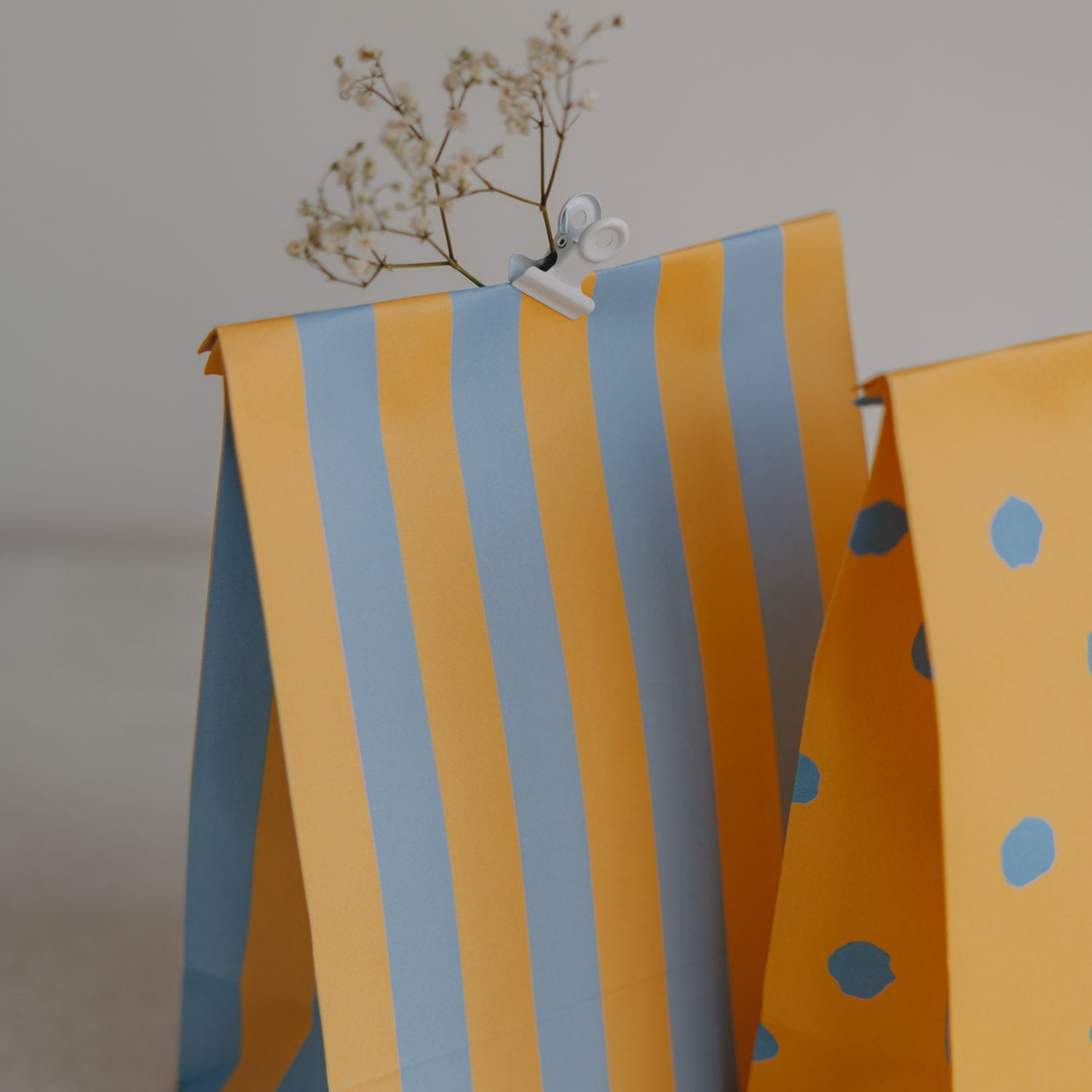 Papiertüte aus Papier: gelb-blau gestreift, daneben gelbe Tüte mit blauen Punkten