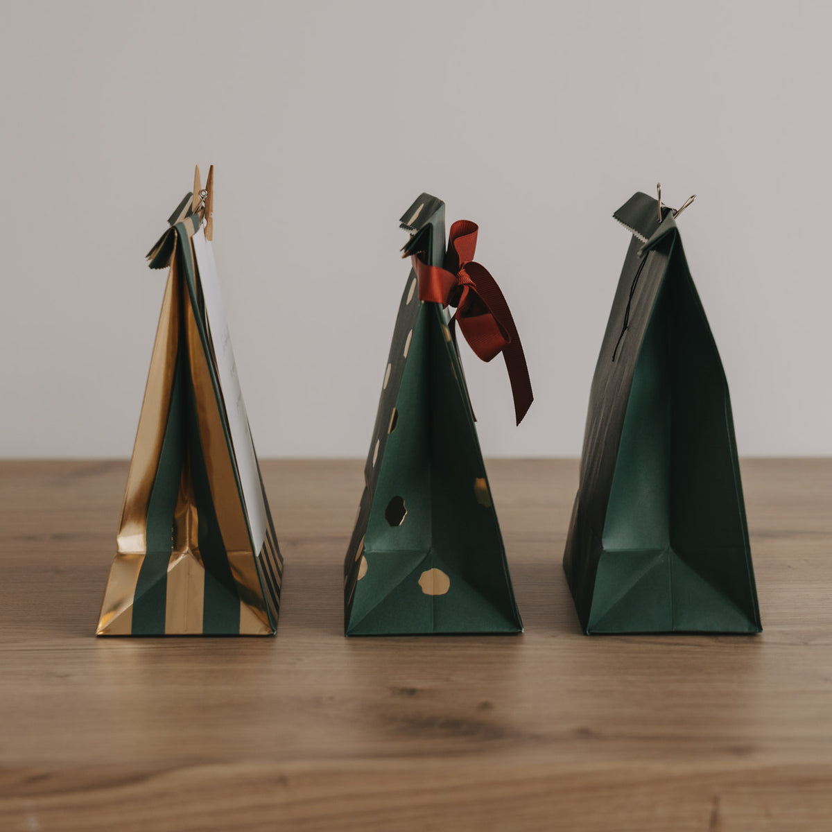 Drei kleine Papiertüten mit Weihnachtsdesign in Grün, Gold und Akzenten in Rot