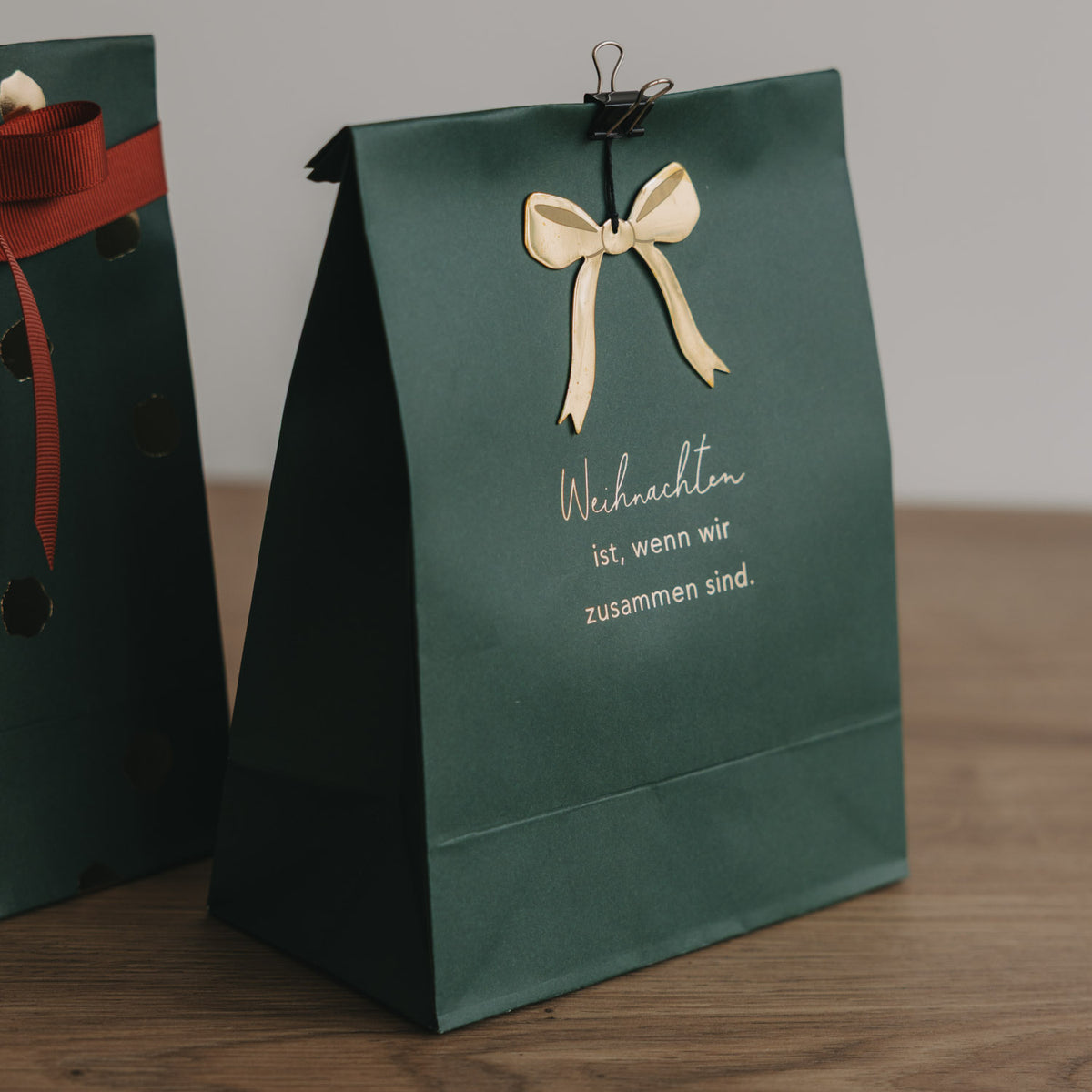 Grüne Weihnachtspapiertüte (S) mit Schleife und Aufdruck „Weihnachten ist, wenn wir zusammen sind.“