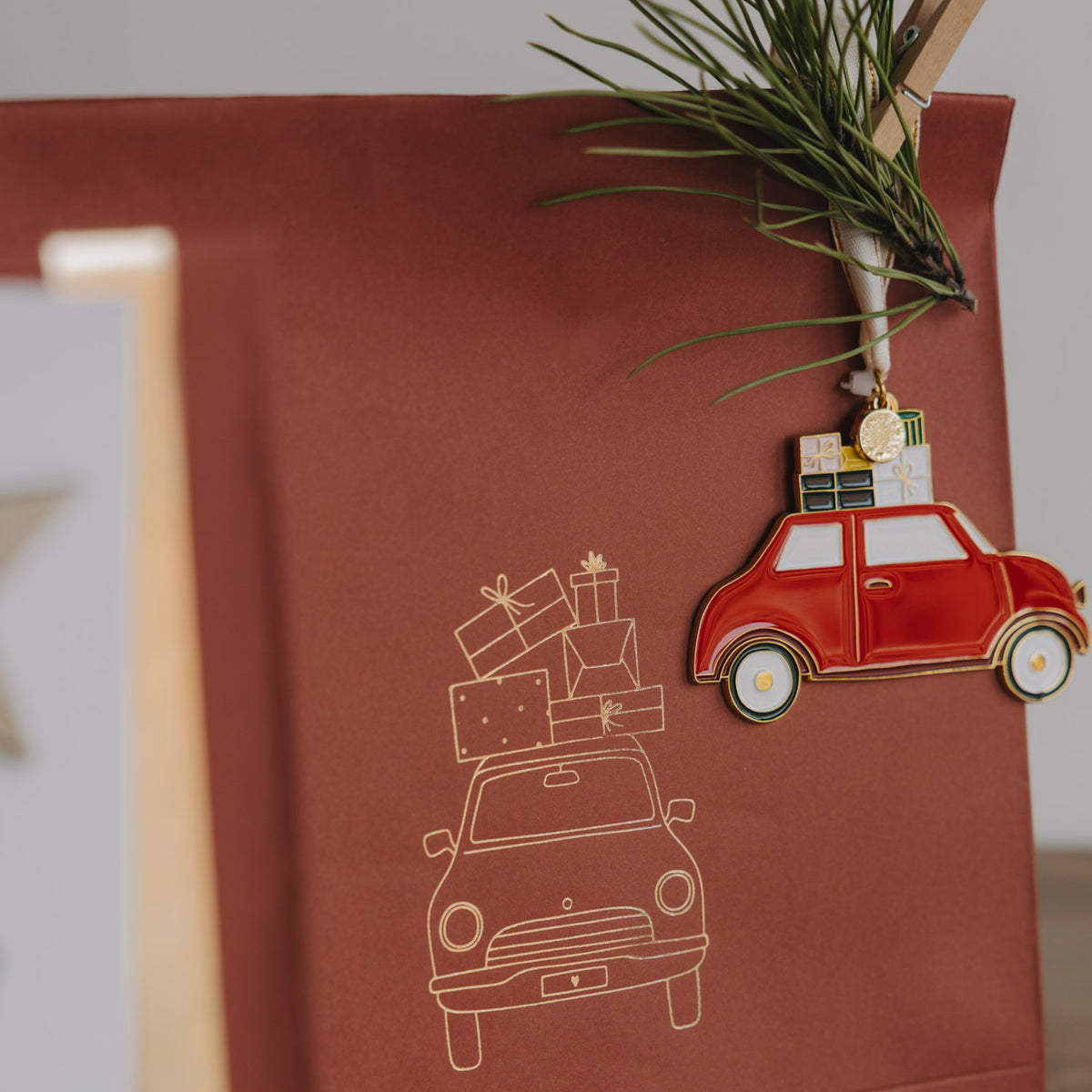 Rote Papiertüte mit Linienzeichnung von Auto/Feuerwehr und Anhänger an der Klammer