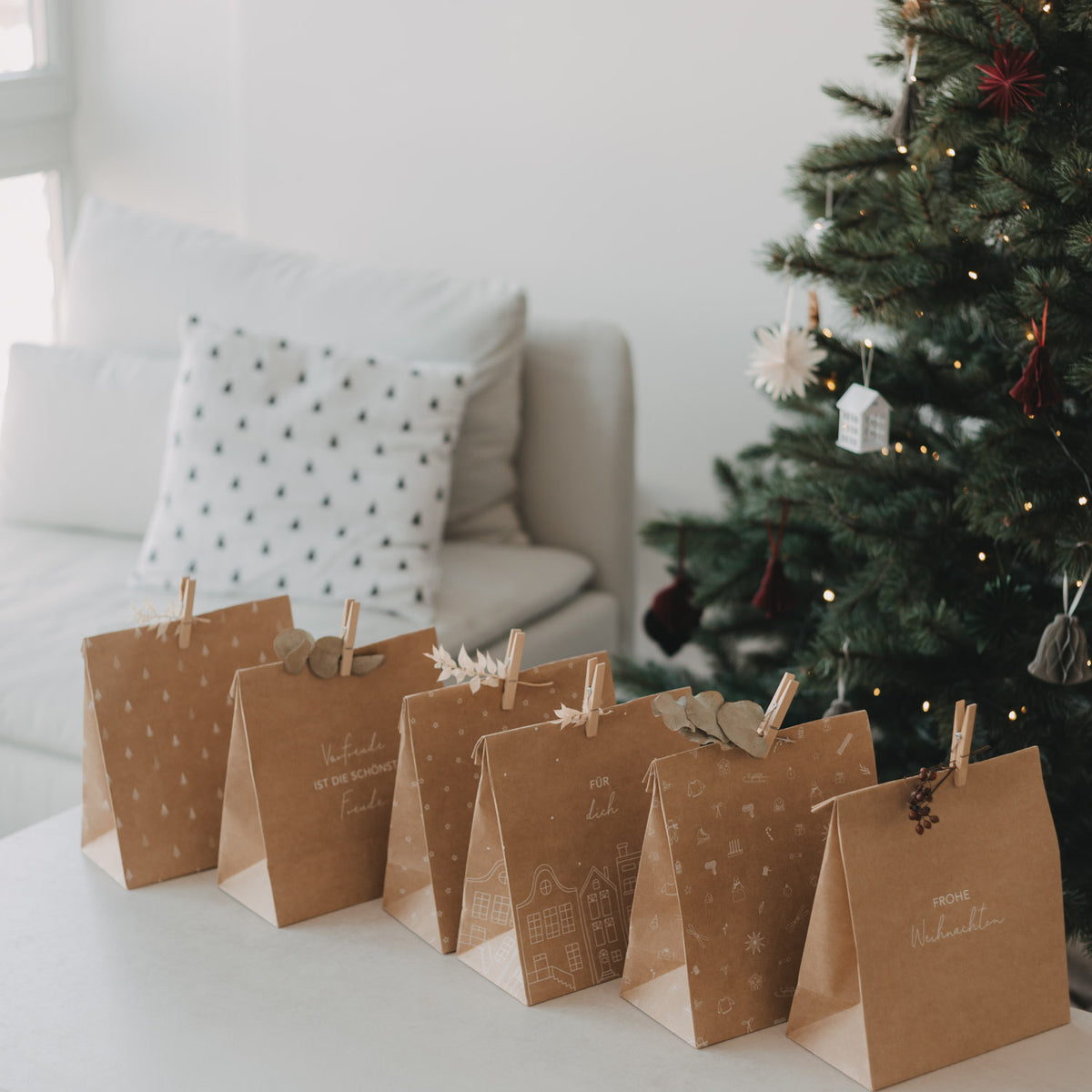Mehrere braune Papiertüten mit weißen Aufdrucken und Weihnachtsmotiven, aufgereiht