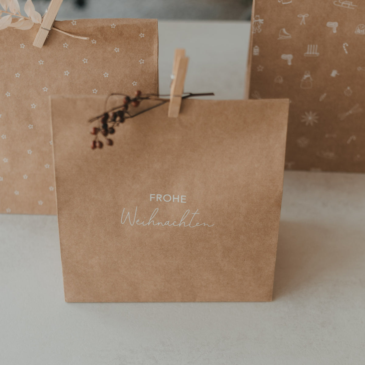 Braune Papiertüte mit Aufdruck „Frohe Weihnachten“ in Weiß, mit Klammer oben