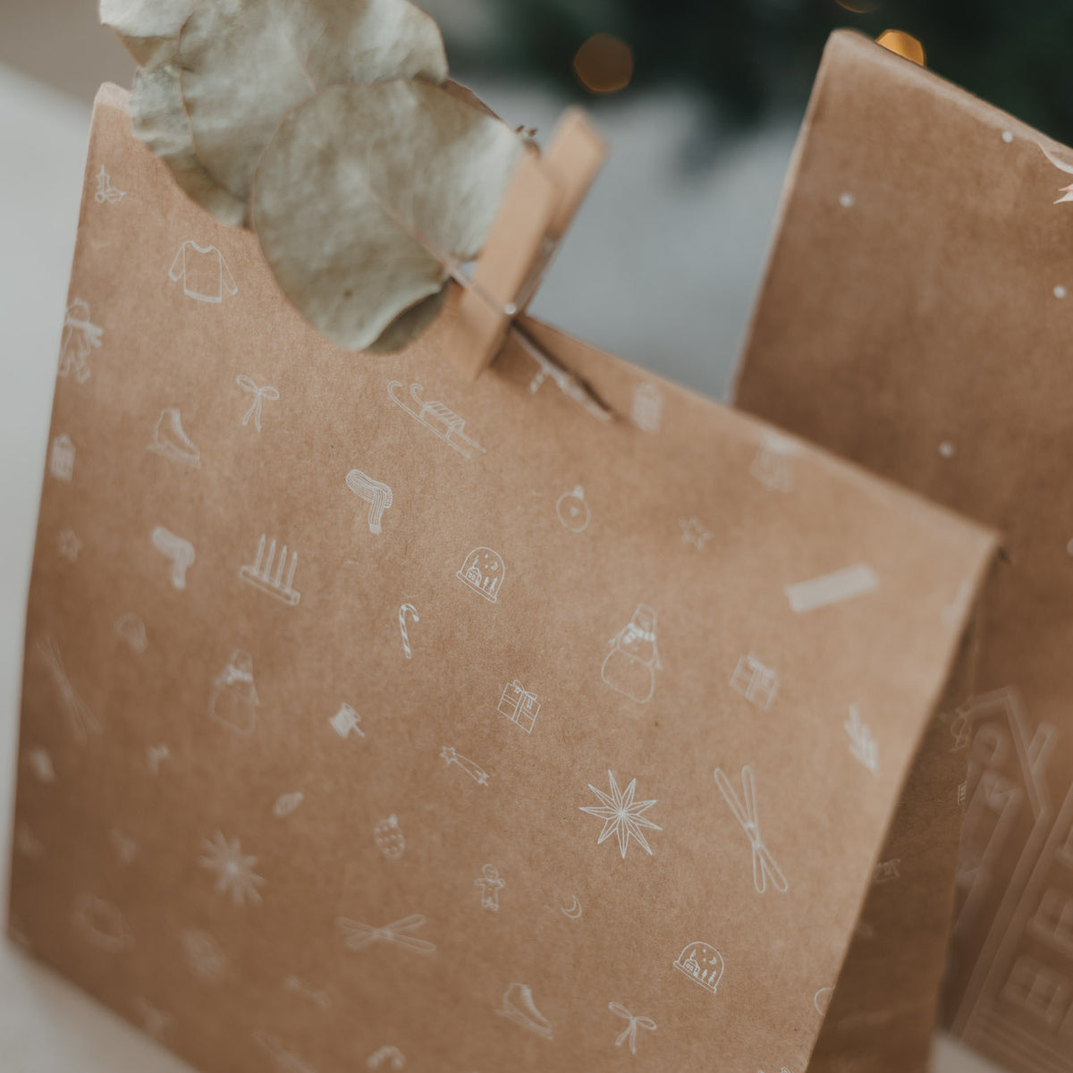 Braune Papiertüte mit weißen Weihnachts-Symbolen, von vorn mit Griff und Verschluss
