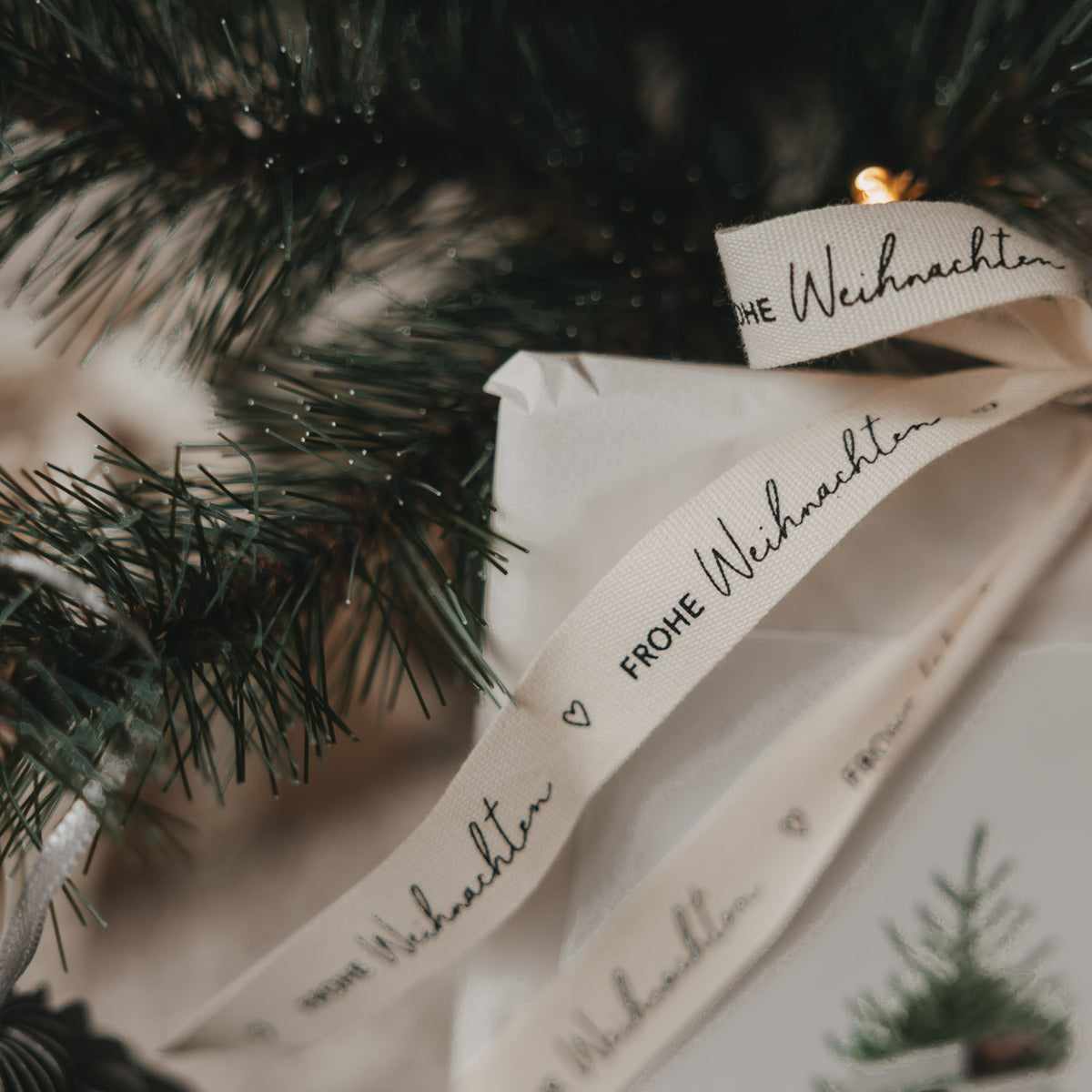 Geschenkband mit „FROHE WEIHNACHTEN“ über die Geschenkverpackung gelegt