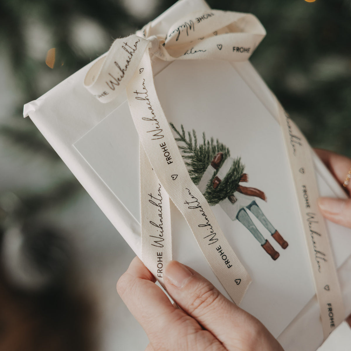 Geschenkband mit Schriftzug „FROHE WEIHNACHTEN“ und Schleife am Geschenkbeutel